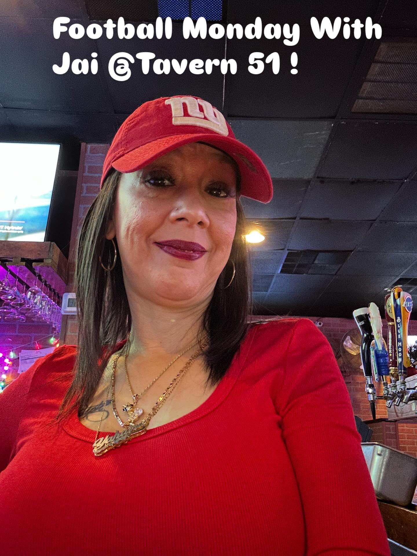 Jai behind the bar at Tavern 51, wearing a red cap and top